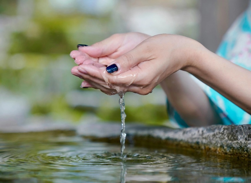 A woman cupping water from a pond.