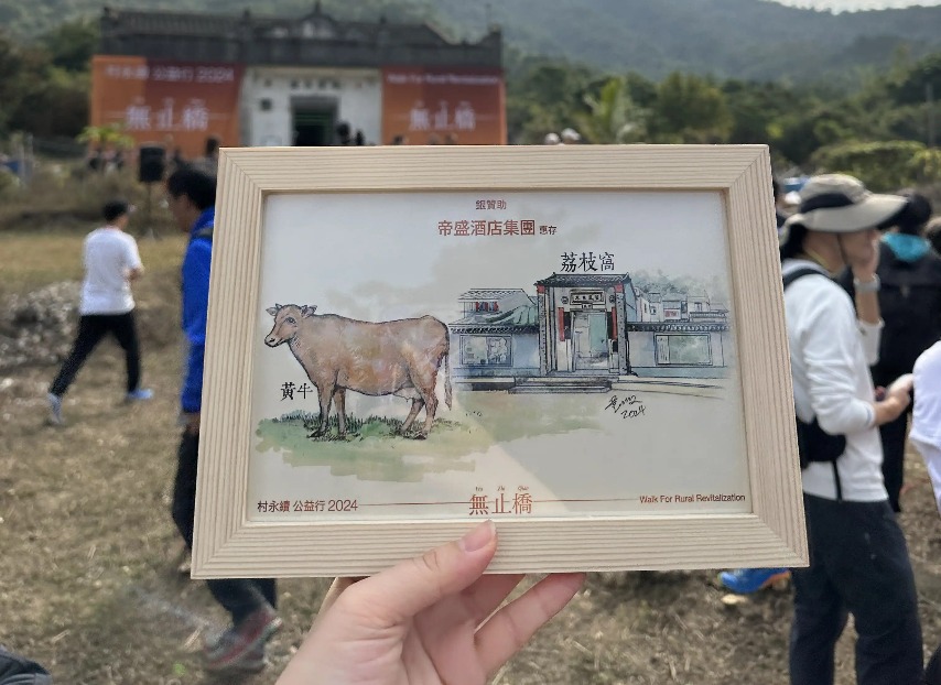 Person holding a framed photo of and illustrated cow and a building.